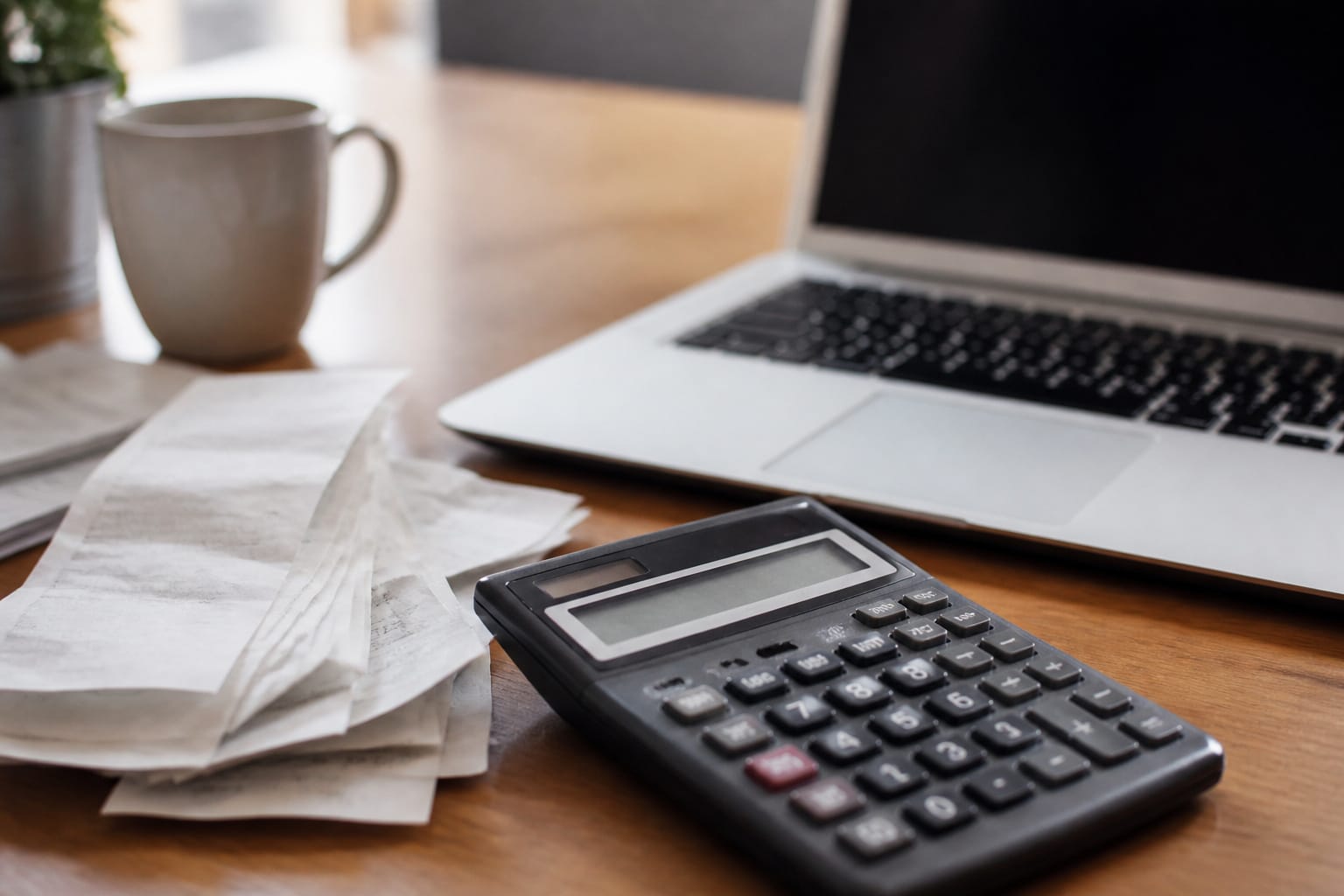 A calculator and receipts beside a computer