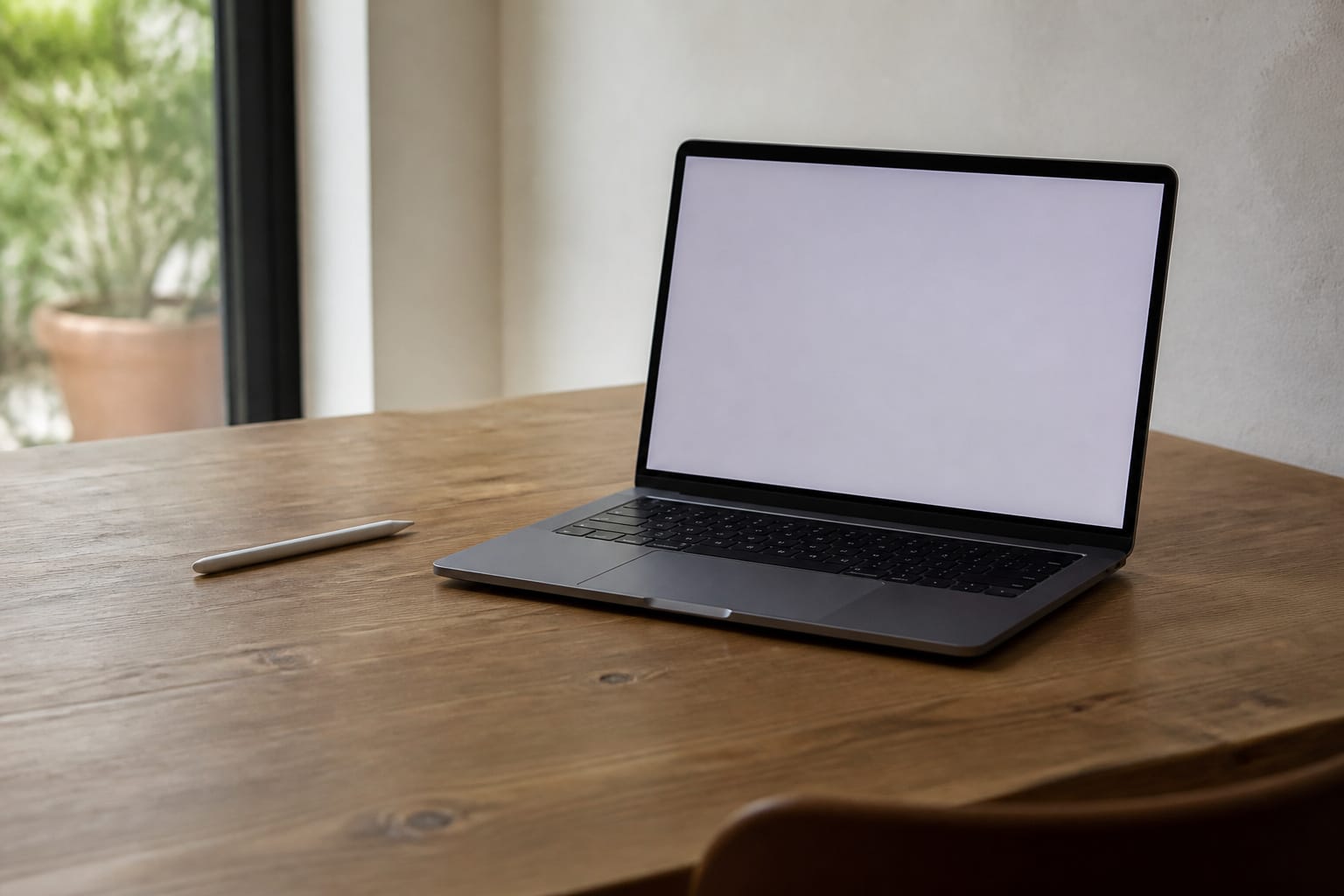A laptop with a plain screen beside a stylus left unused