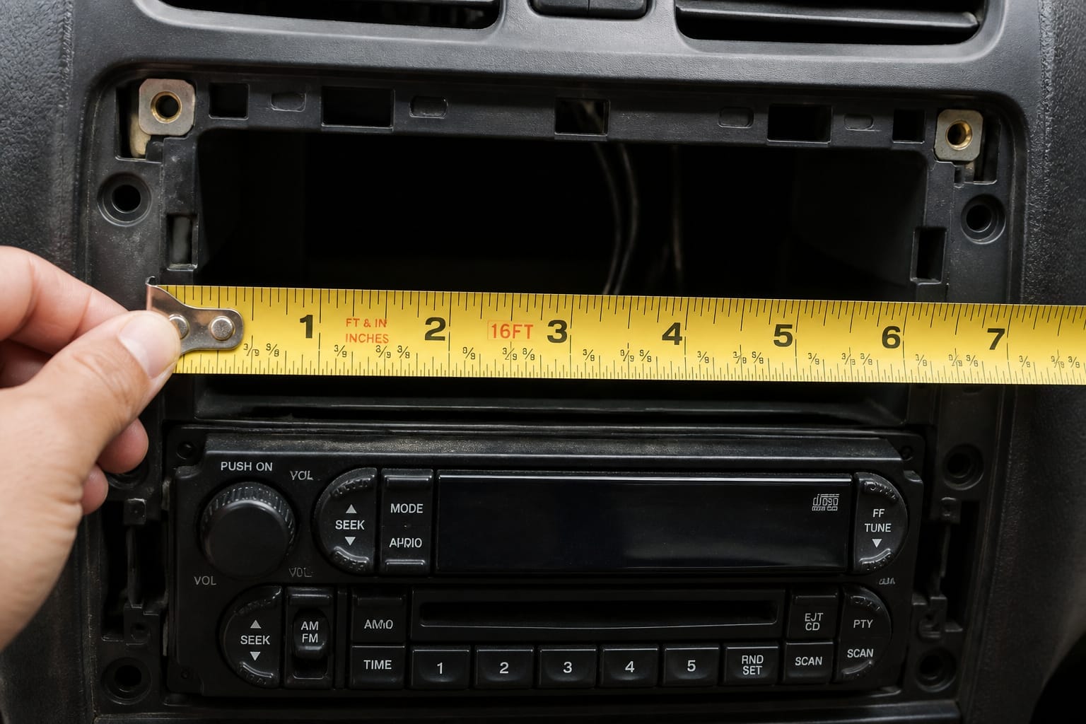 Measuring a car's dashboard stereo opening with a tape measure