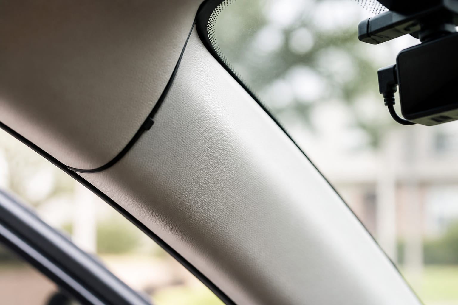 Dash cam power cable tucked neatly along a car's A-pillar trim