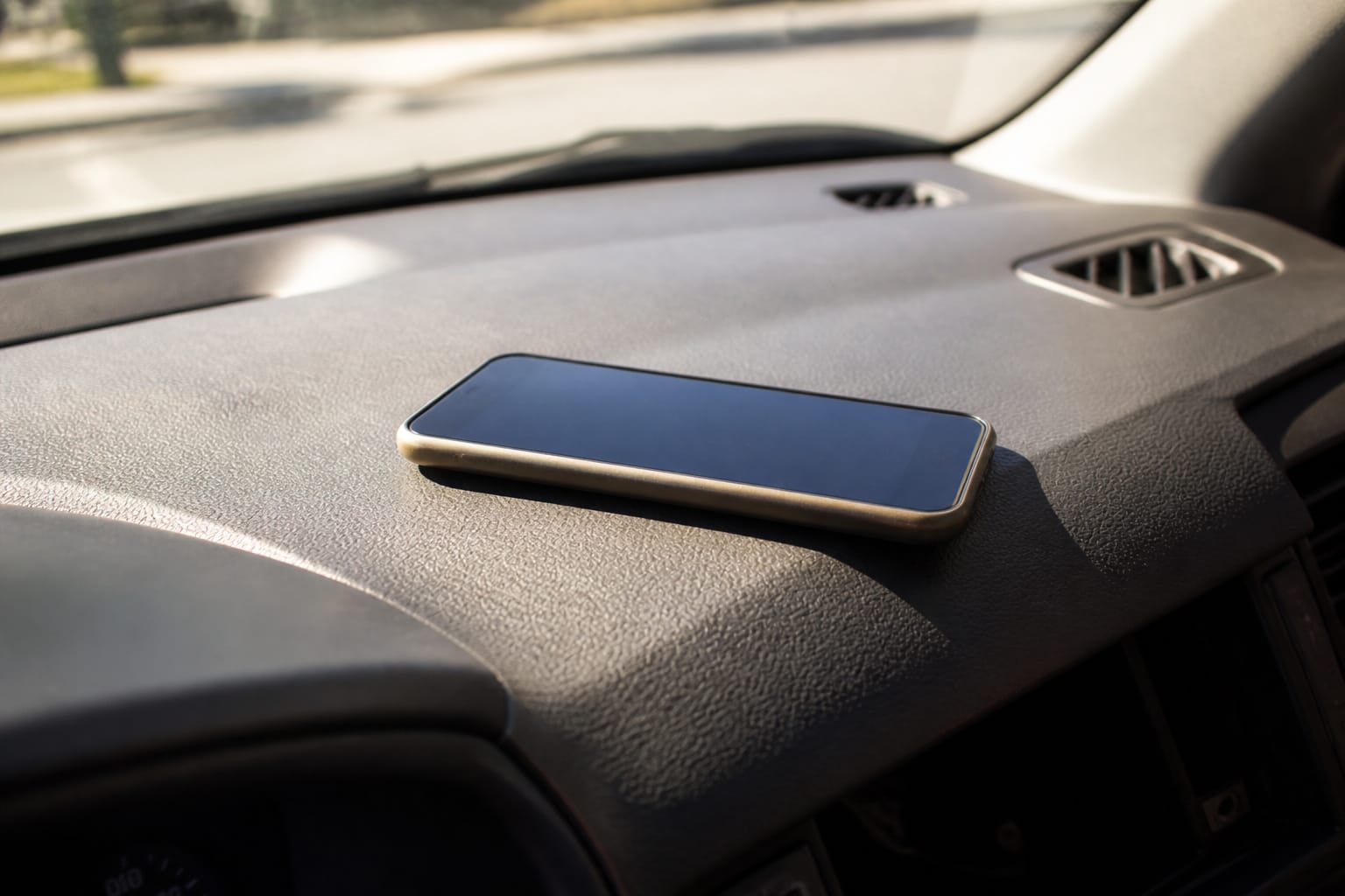 Smartphone resting on a car dashboard in direct sunlight