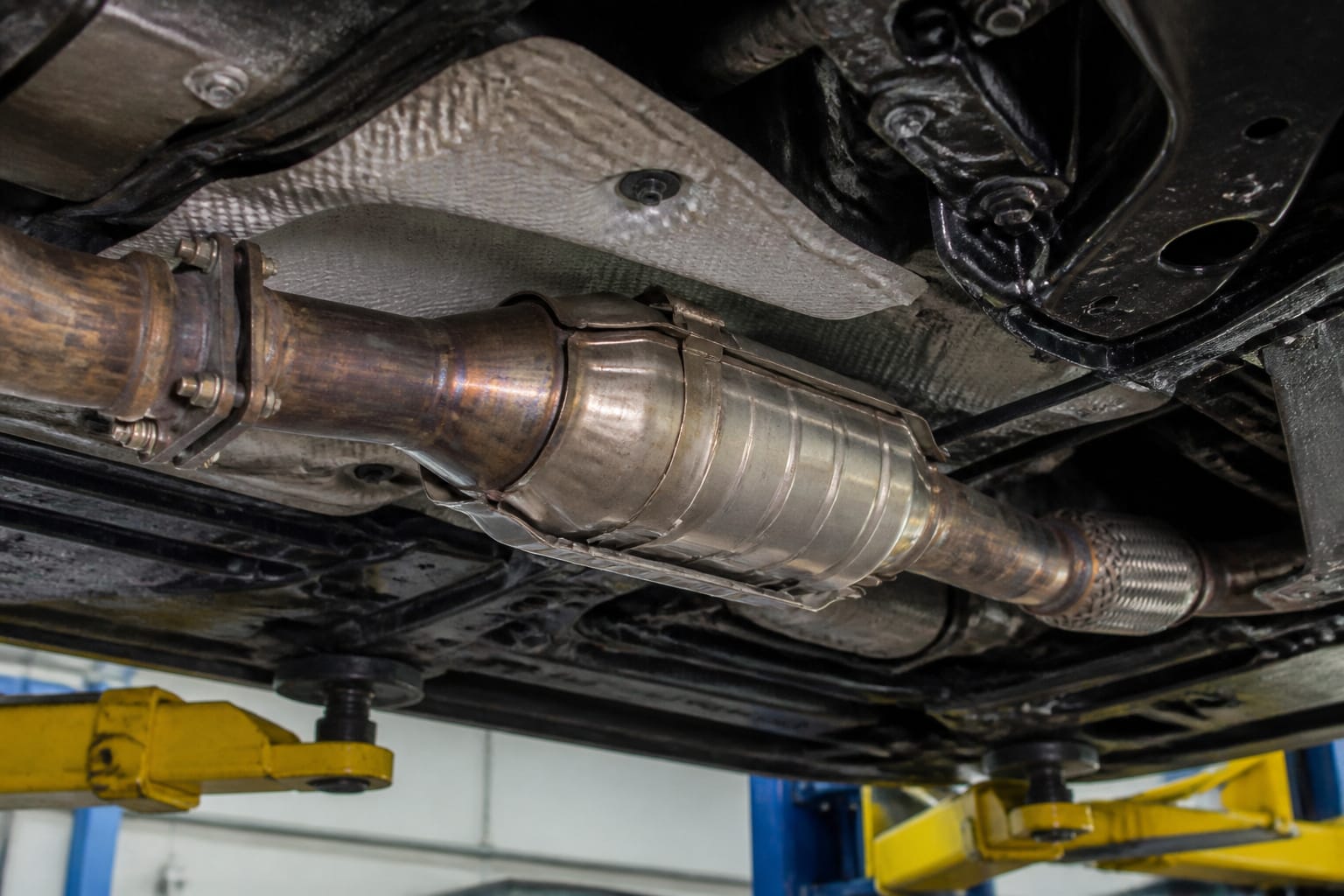 Underside view of a car's catalytic converter and exhaust system on a lift