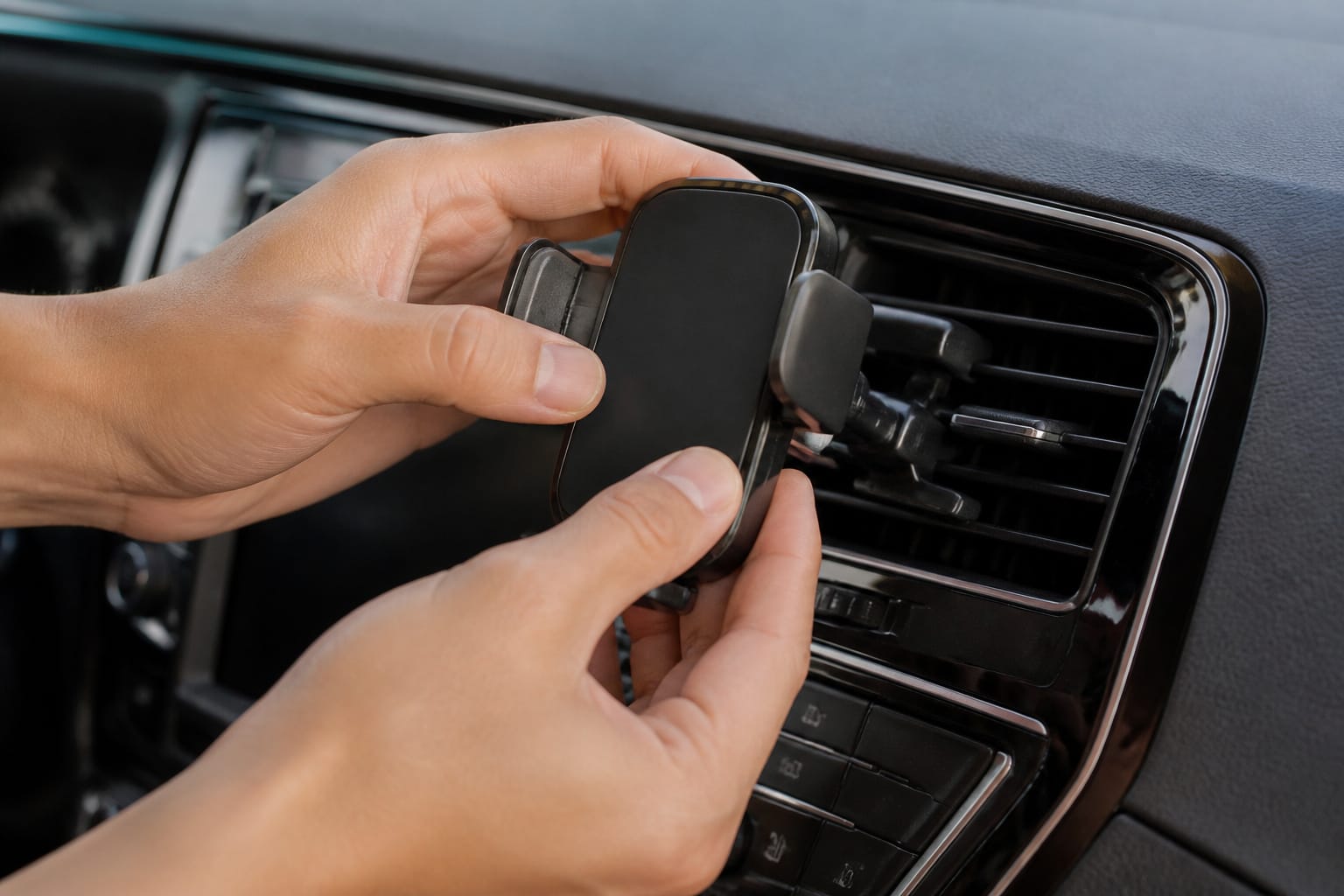 Hands testing the stability of a car phone mount on an air vent