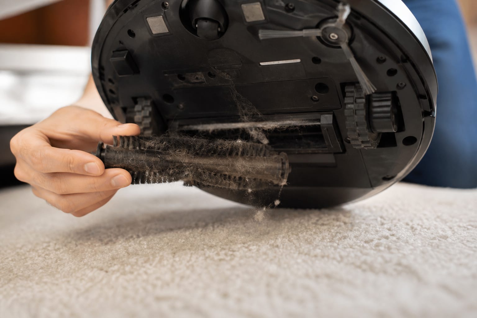 Robot vacuum brush roll and suction intake shown over carpet