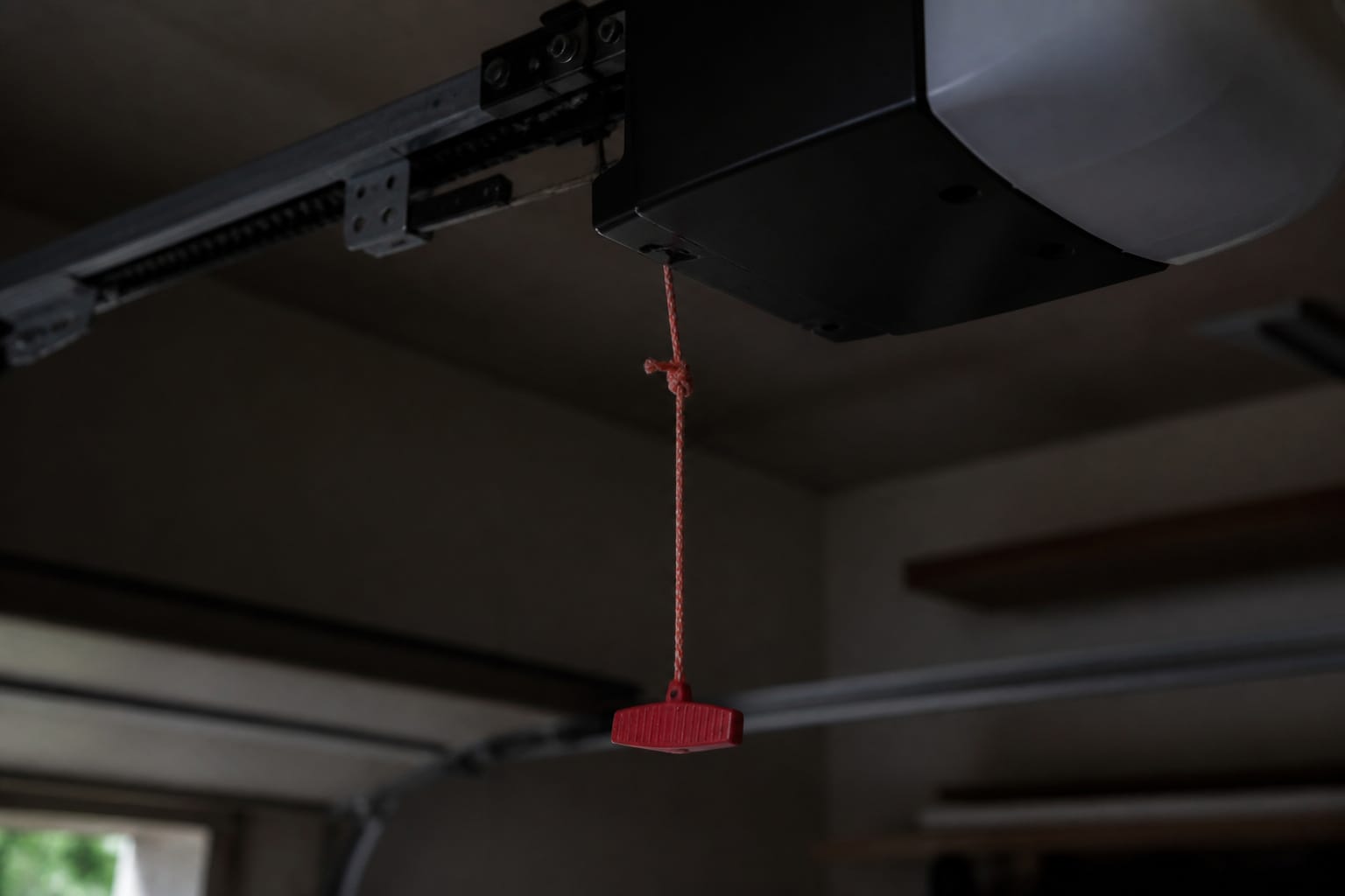 Garage door opener's emergency release cord hanging near the motor unit