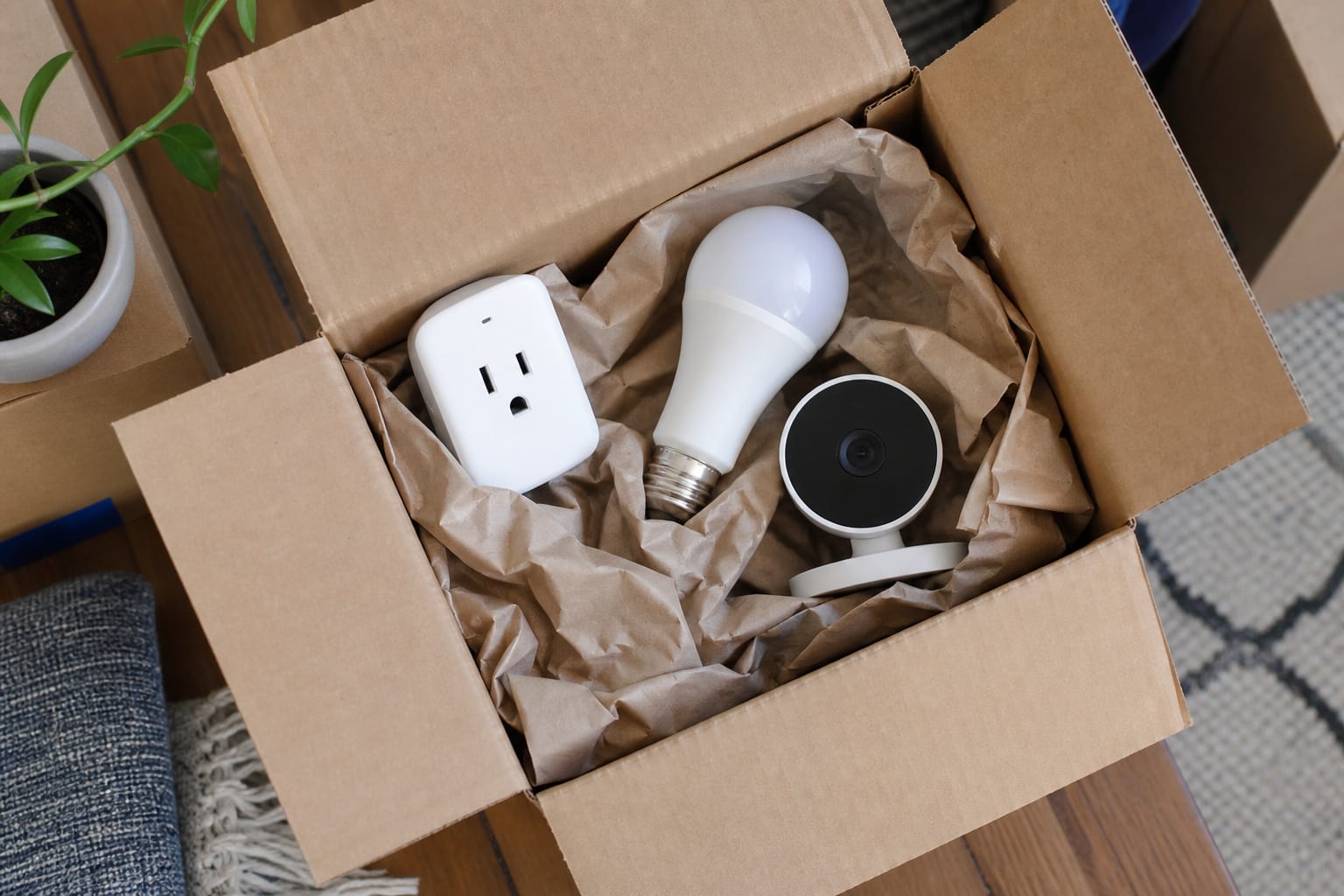 Moving box containing a smart plug, smart bulb, and small camera packed for a move