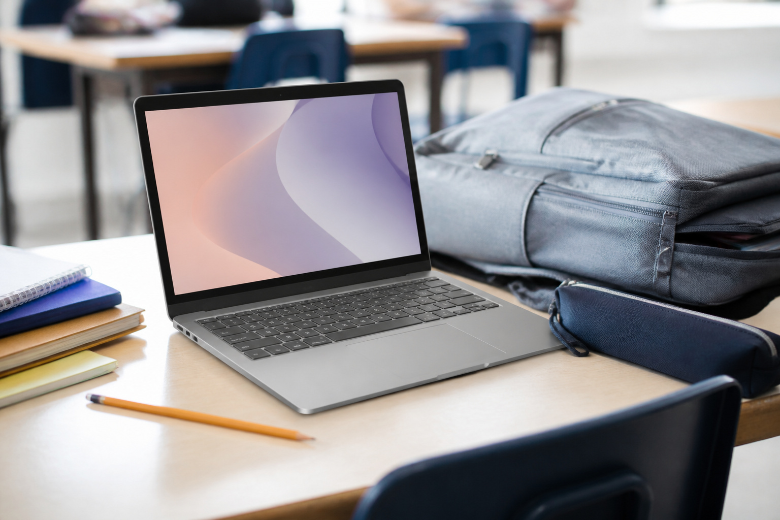 Chromebook-style laptop on a school desk with notebooks and a backpack