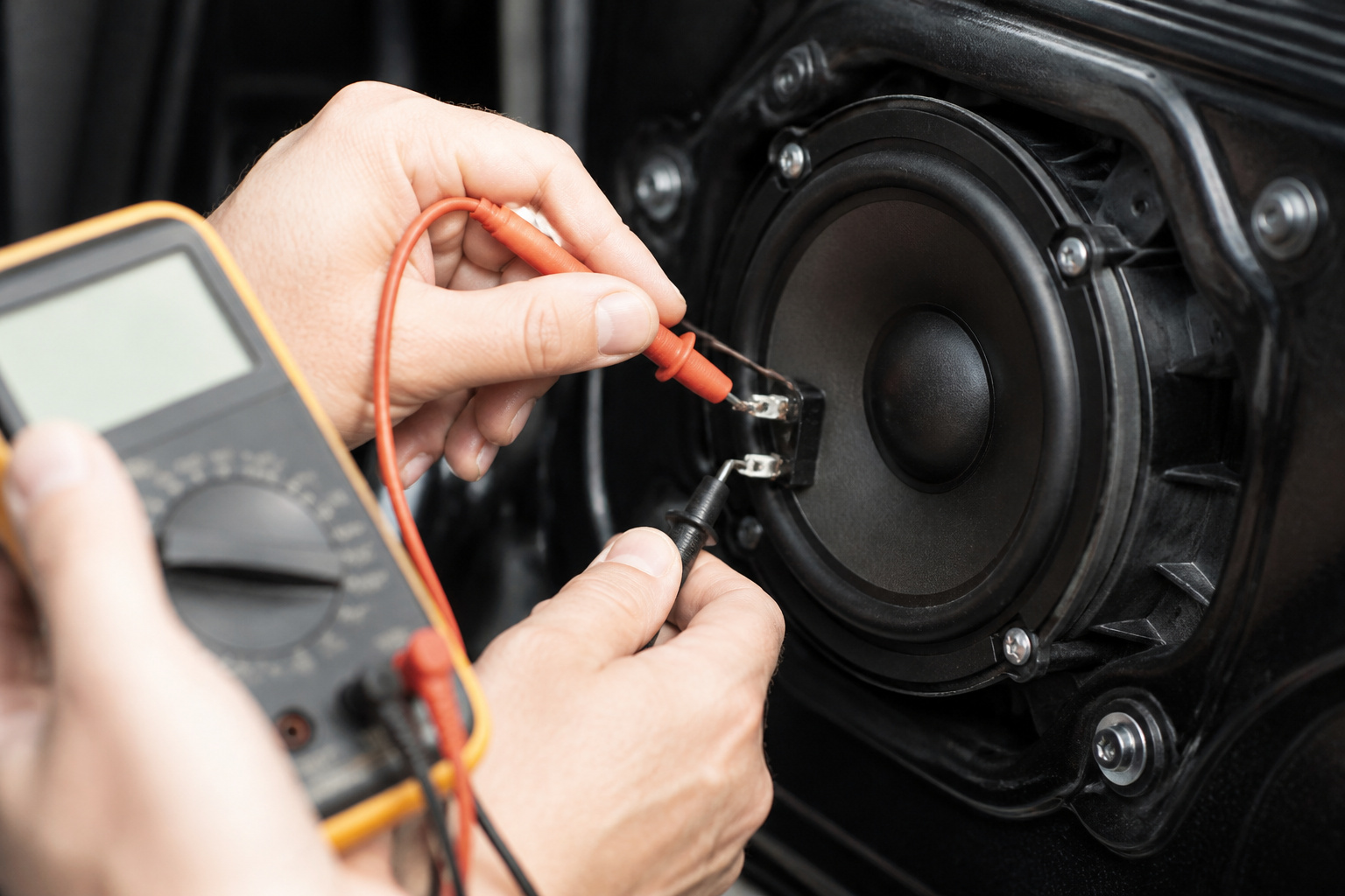 Multimeter probe testing a car speaker terminal