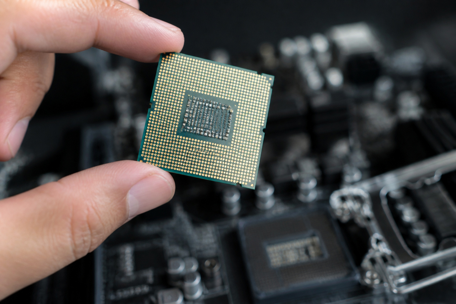 Small CPU chip held above a motherboard