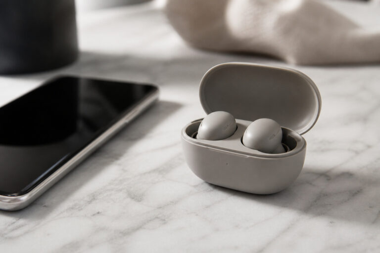 True wireless earbuds in an open charging case beside a smartphone